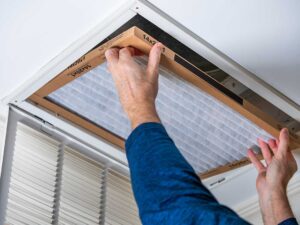 Homeowner changing a pleated air filter in a household return air vent